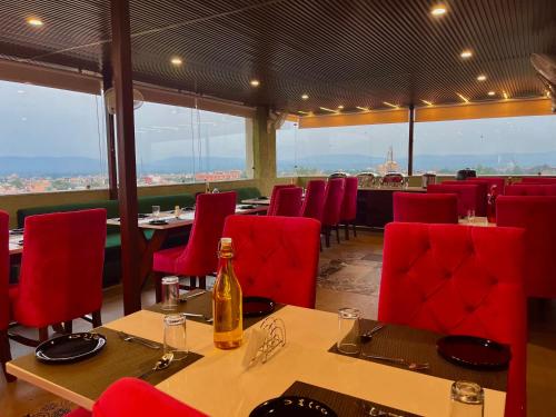 um restaurante com cadeiras e mesas vermelhas e uma garrafa de vinho em Ganges Blossam, Haridwar-Rishikesh Road - A Four Star Luxury Hotel em Rishikesh
