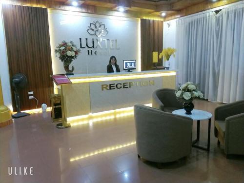ハノイにあるLuxTel Hotel Tây Hồのホテルのロビーには、フロントデスクと椅子があります。
