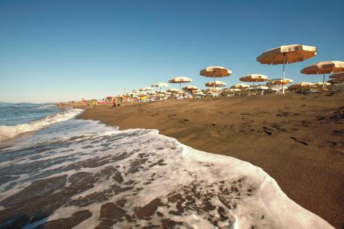 a beach with umbrellas and chairs and the ocean at Gitavillage Club degli Amici in Pescia Romana