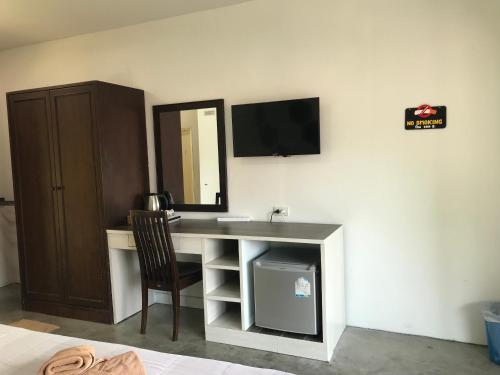 a desk with a chair and a television on a wall at PP Midnight Hotel in Phi Phi Don