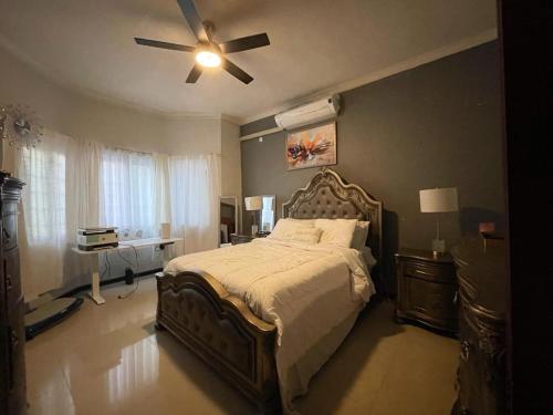 Schlafzimmer mit einem großen Bett und einem Deckenventilator in der Unterkunft Idyllic Condo in Liguanea in Kingston