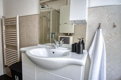 a white bathroom with a sink and a towel at Homefy Sleep & Relax Apartment mit frei parken, in Toplage in Essen