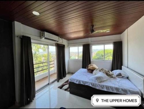 um quarto com uma cama num quarto com janelas em The Upper Homes em Guwahati