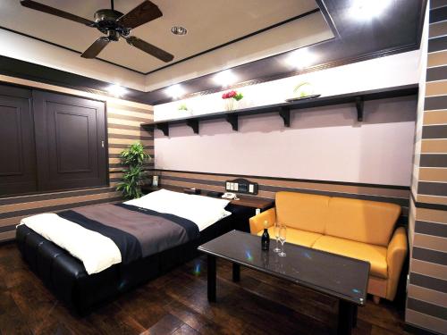 a bedroom with a bed and a table and a couch at Restay Tokushima Aine (Adult Only) in Tokushima