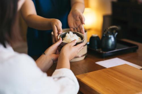 a woman eating food in a bowl on a table at Nipponia 甲佐 疏水の郷 in Kosa