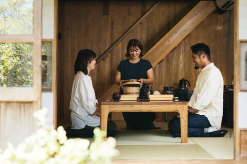 a group of three people sitting around a table in a room at Nipponia 甲佐 疏水の郷 in Kosa