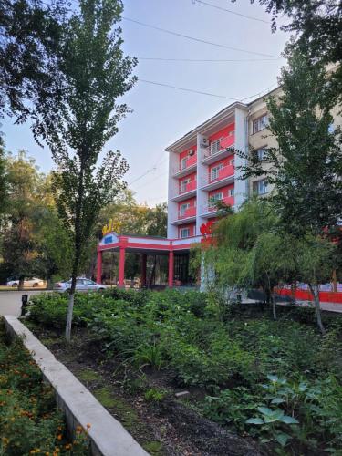 ein Gebäude mit einem roten Balkon in einem Park in der Unterkunft Гостиница ИЛЕК in Aqtöbe