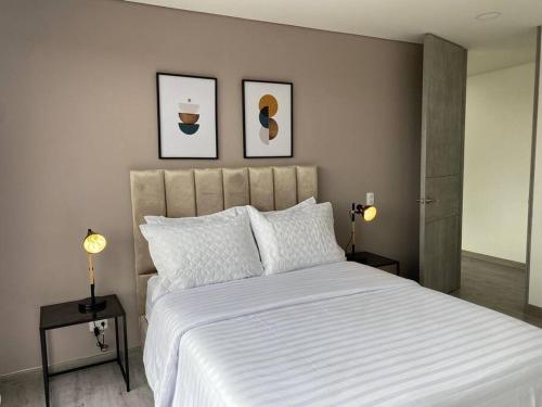 - une chambre avec un grand lit blanc et deux lampes dans l'établissement Amplio apartamento con excelente vista, à Bogotá