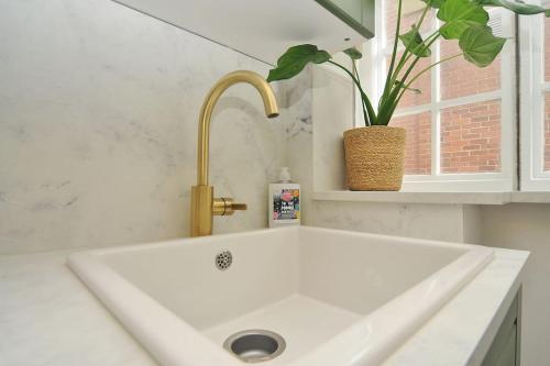 um lavatório branco com uma torneira e um vaso de plantas em Stylish apartment, Barbican em Plymouth