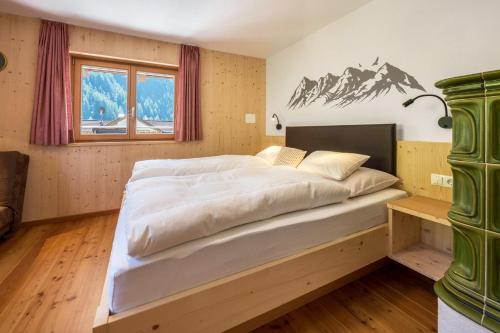 1 dormitorio con 1 cama grande y un mural de montaña en la pared en Ferienhaus Nairz Alpenrose, en Predoi