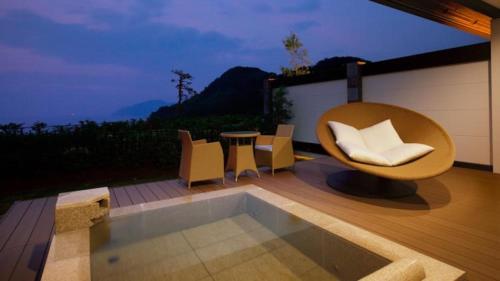 a patio with a chair and a table and a pool at Fugaku Gunjo in Izu