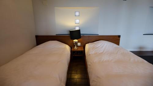 two twin beds in a room with a side table at Fugaku Gunjo in Izu