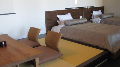 a hotel room with a bed and a table and chairs at Fugaku Gunjo in Izu