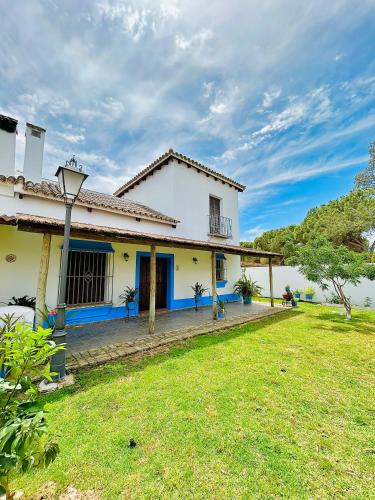 a large white house with a grass yard at Casa La Retama - Pequeño Rocio in El Rocío