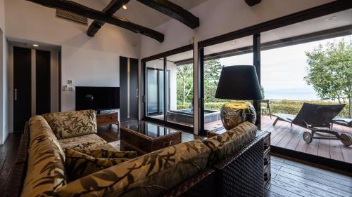 a living room with a couch and a large window at Fugaku Gunjo in Izu