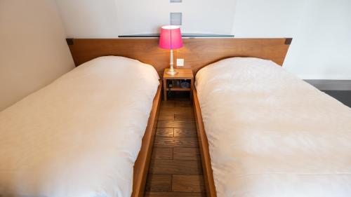 two beds in a room with a lamp on a table at Fugaku Gunjo in Izu