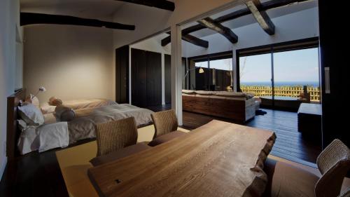 a bedroom with a bed and a table and a large window at Fugaku Gunjo in Izu