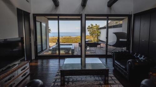 a living room with a couch and a table and a television at Fugaku Gunjo in Izu