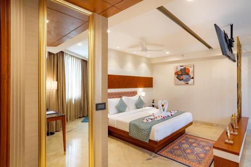 een slaapkamer met een bed, een bureau en een televisie bij Inde Signature Jaipur in Jaipur