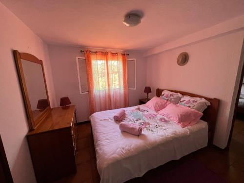 um quarto com uma cama com almofadas cor-de-rosa e um espelho em Vivenda Ribeiro - Curral das Freiras em Curral das Freiras