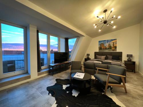 a bedroom with a bed and a living room with windows at Talgarten Penthouse 1 in Erfurt
