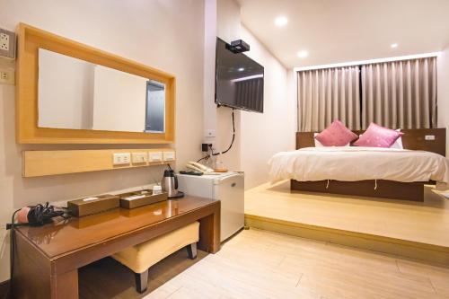a bedroom with a bed and a desk and a mirror at Mei Jia Mei Hotel in Jiaoxi