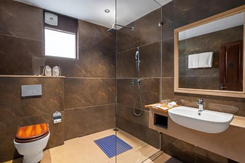 W łazience znajduje się toaleta, umywalka i lustro. w obiekcie Brij Anayra Dharamshala - A Himalayan Luxury Retreat w mieście Dharamsala