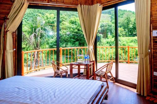 ein Schlafzimmer mit einem Bett und einen Balkon mit einem Tisch und Stühlen in der Unterkunft Little Bee in Luong Son