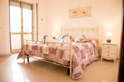 een slaapkamer met een bed met een deken en een raam bij Locorotondo Home Holidays in Locorotondo