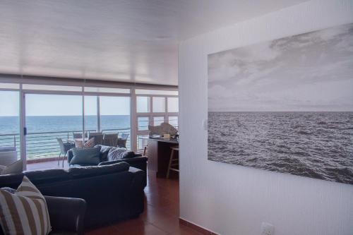 a living room with a painting of the ocean at Palm Cove - 16 Chakas Cove, Literally on the Beach in Ballito