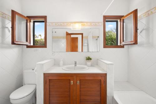 a bathroom with a sink and a toilet and a mirror at Villa Michaela in Sant Lluis