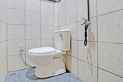 een badkamer met een toilet en een telefoon aan de muur bij OYO 92606 Djoglo Boto Homestay Syariah in Yogyakarta