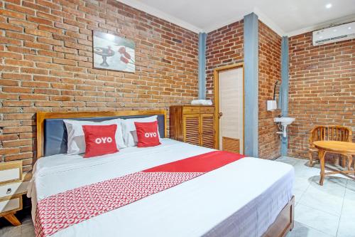 una camera da letto con un muro di mattoni e un letto con cuscini rossi di OYO 92606 Djoglo Boto Homestay Syariah a Yogyakarta