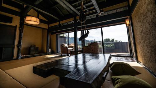 a living room with a table and a large window at 森の入り江の離れ宿 無雙庵枇杷 in Toi