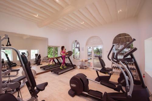 a woman standing in a gym with several tread machines at Diamonds Mapenzi Beach in Kiwengwa