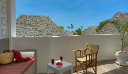 a room with a couch and a chair on a balcony at Diamonds Mapenzi Beach in Kiwengwa