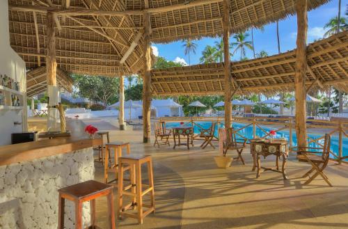 a resort with tables and chairs and a pool at Diamonds Mapenzi Beach - All Inclusive in Kiwengwa