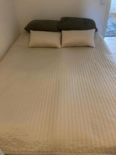 ein Bett mit weißer Bettwäsche und Kissen darauf in der Unterkunft Mehri in Uppsala