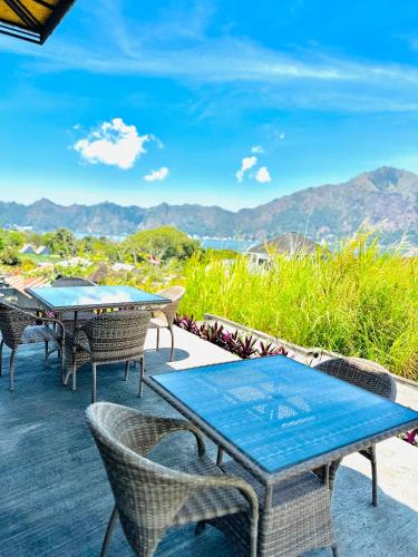 a patio with tables and chairs and mountains in the background at Batur Volcano Guesthouse in Kintamani