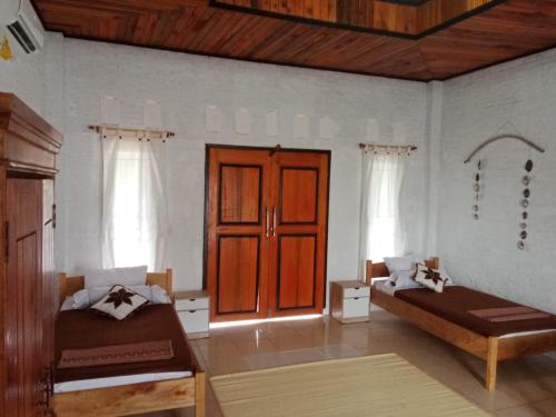 una camera con due letti e una porta in legno di Rumah Pantai Krui a Wainapal