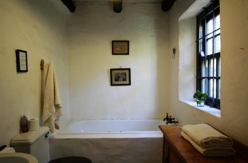 baño con bañera, aseo y ventana en The Little Farmhouse, en Stanford