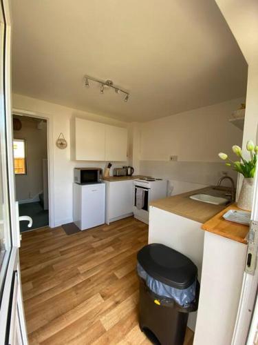 a kitchen with white appliances and a wooden floor at Honey Cottage in Totland