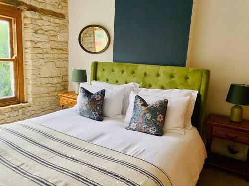 Schlafzimmer mit einem Bett mit einem grünen Kopfteil und Kissen in der Unterkunft Cotswold Home over 4 floors - perfect for Families Friends Contractors in Chipping Norton