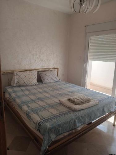 a bed in a room with a window and a bedspread at Les Jasmins de Hammamet in Hammamet