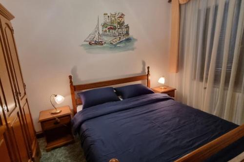 a bedroom with a bed with blue sheets and a painting on the wall at APARTMENT GORDANA A4+2 FOR 6 PAX NATURE PARK in Lokve