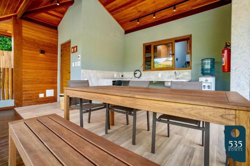 une salle à manger avec une table et des bancs en bois dans l'établissement Conforto e comodidade em Praia do Forte, à Mata de São João