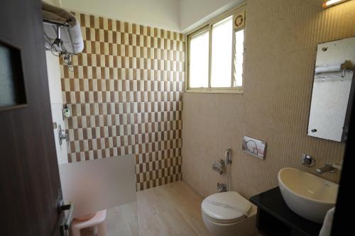 a bathroom with a toilet and a sink at Hotel Metropolis in Hubli