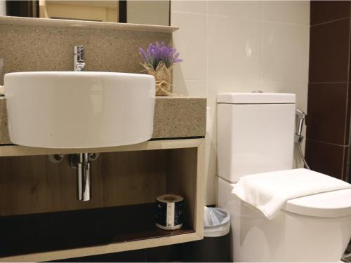 y baño con aseo blanco y lavamanos. en Aqueen Prestige Hotel Lavender en Singapur