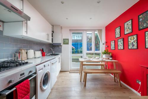 uma cozinha com paredes vermelhas e uma mesa de madeira em ALTIDO Striking flat with charming garden em Londres