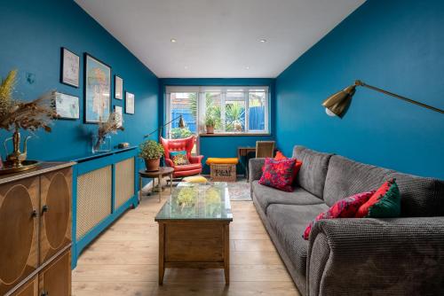 uma sala de estar com um sofá e uma parede azul em ALTIDO Striking flat with charming garden em Londres